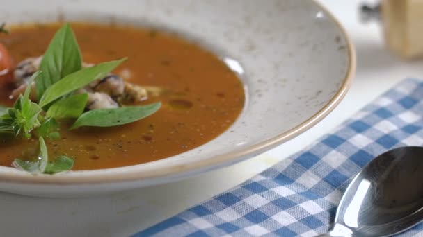 Sopa de tomate com frutos do mar decorada com folhas de manjericão e tomate cereja em prato branco na mesa . — Vídeo de Stock