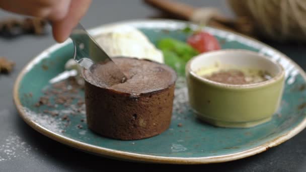 Teplý čokoládový dortík fondán podávaný se zmrzlinou. Dort je řez s nožem. Tekutý krém odteče. Zpomalený pohyb. — Stock video