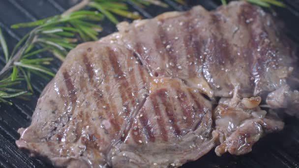 Rindersteak auf dem Grill wird mit schwarzem Pfeffer bestreut. Zeitlupe. — Stockvideo