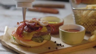 Popüler fastfood: taze et ile yumuşak hamburger. Aşçı ketçap dökülen. Ağır çekim.