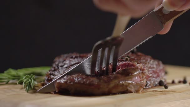 Movimento lento. Bife suculento, fresco e apetitoso cortado com uma faca, segurando o garfo. Close-up. Bife grelhado em fatias na tábua de corte . — Vídeo de Stock