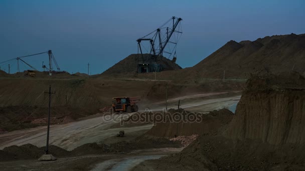 Foto yang lebar dari operasi tambang dengan ekskavator dragline memuat bijih di latar belakang saat senja. Pemandangan belakang truk sampah lewat. Tambang Bauxite . — Stok Video