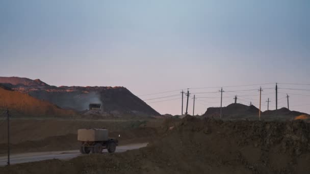 Weitwinkelaufnahme des Bergwerks mit Baggern, die in der Abenddämmerung Erz verladen. Rückansicht eines vorbeifahrenden Muldenkippers. Bauxitabbau. — Stockvideo