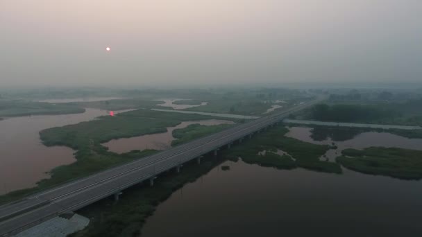 空撮。川、道路橋、木と信じられないほどの太陽とフィールドを持つ美しい風景。朝の霧. — ストック動画