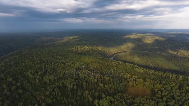 Aerial shot of mountains covered with coniferous forest with River and sun rays through the clouds. — Stock Video