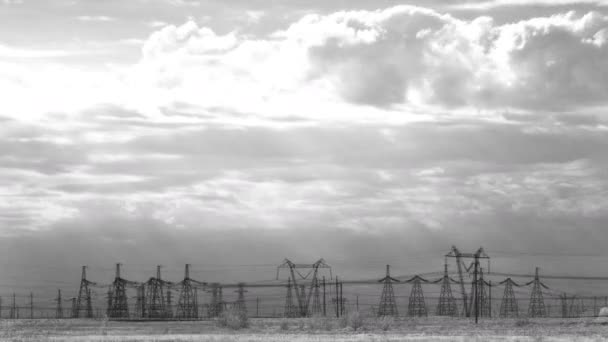 Широкий черно-белый кадр электрических пилонов против временных облаков на закате . — стоковое видео