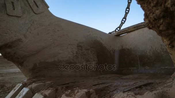 Håndholdt tilt-down close-up skud af dragline gravemaskine spand 15 kubikmeter med massive kæder stående på siden af stenbruddet mod solnedgang på den blå himmel . – Stock-video