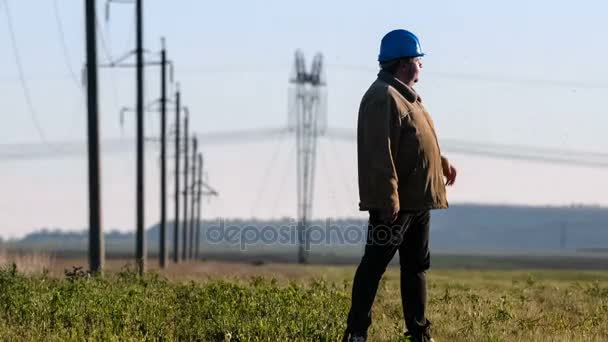 Szeroki strzał poważne inspektora w kask, sprawdzanie elektrycznych bieżących planów ankiety podczas inspekcji. — Wideo stockowe