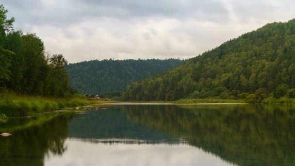 Zeitraffer von bewegten grauen Wolken, die sich auf einem See spiegeln, der von einem Bergwald umgeben ist. — Stockvideo