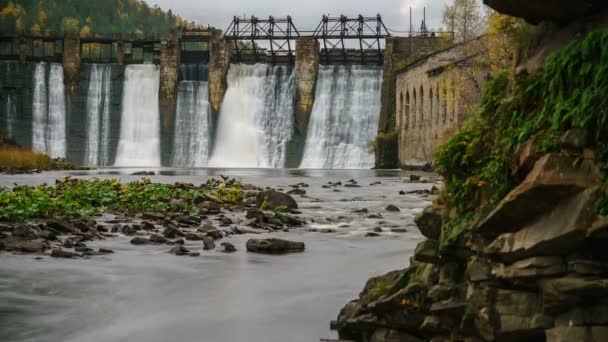 Time-lapse pan water giet zoals linten over de oude macht generatie dam met weelderige groene mos bedekt rotsen op de achtergrond. — Stockvideo