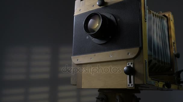 Bijhouden van lage hoek uitzoomen schot van oude vintage houten foto camera verlichting door zonlicht door de blinds in de grijze achtergrond. — Stockvideo