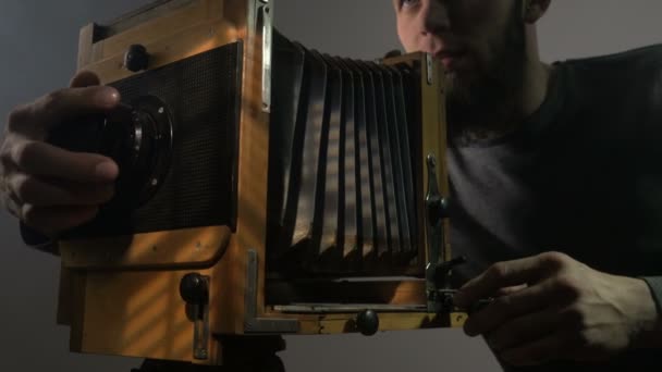 Vista a basso angolo del fotografo barbuto regolazione vecchia macchina fotografica in legno vintage e scattare foto . — Video Stock