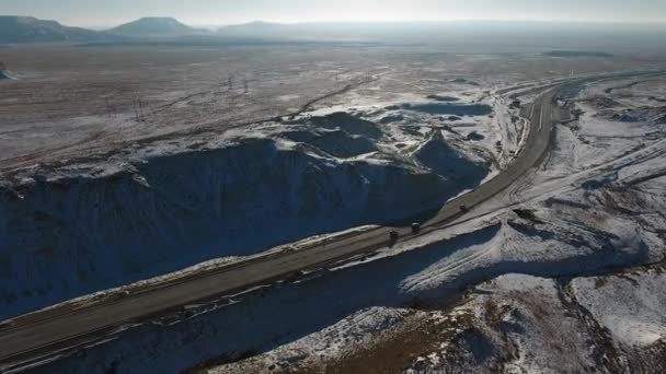Aerial view of trucks and suvs moving along the highway in the desert in winter. Western Kazakhstan, Mangyshlak Peninsula. — Stock Video