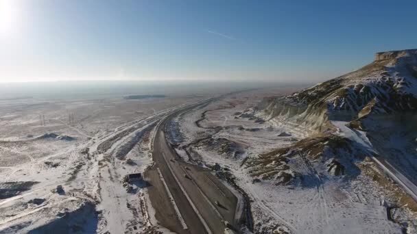 Vista aérea de caminhões e suvs se movendo ao longo da estrada no deserto no inverno. Cazaquistão Ocidental, Península de Mangyshlak . — Vídeo de Stock