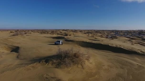 Vista aérea do suv em movimento no deserto coberto de neve no inverno. Cazaquistão Ocidental, Península de Mangyshlak . — Vídeo de Stock