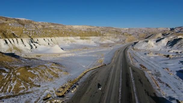 Aerial view of three suvs moving along the highway in the snow-coversd sandy mountains in winter. Western Kazakhstan, Mangyshlak Peninsula. — Stock Video