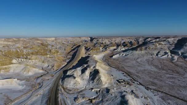 Aerial view of three suvs moving along the highway in the snow-coversd sandy mountains in winter. Western Kazakhstan, Mangyshlak Peninsula. — Stock Video