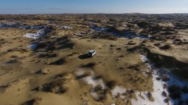 Luchtfoto van suv bewegen door de sneeuw bedekte woestijn in de winter. West Kazachstan, Mangyshlak schiereiland. — Stockvideo