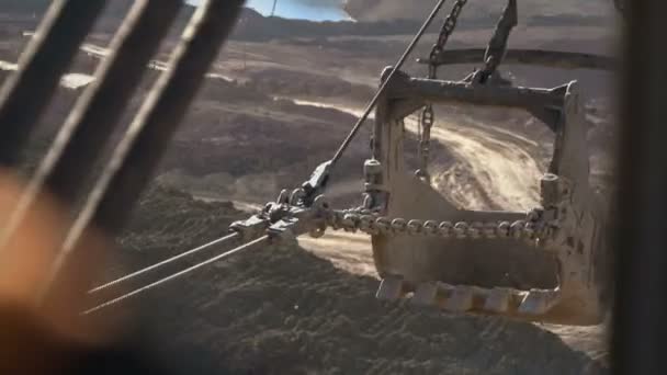 Tiro de mano de cucharón de excavadora dragalina 15 metros cúbicos con cadenas masivas que dibujan mineral en el lado de la cantera contra la puesta del sol. Vista desde la cabina . — Vídeos de Stock