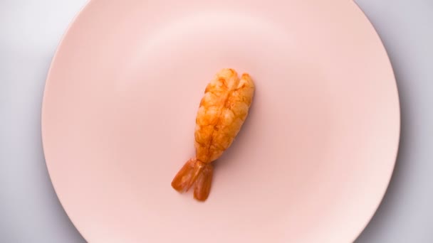 Vue du dessus des crevettes nigiri sushi sur la plaque rose filante . — Video