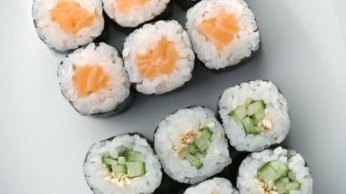 Taze suşi seti dönüyor. Tipik Japon yemeği, pirinç, avokado, somon, ton balığı, karides, soya, balık, havyar. Japon restoran menüsü, Kaliforniya seti. Yukarıdan görüntüle, Üst görünüm, yavaş