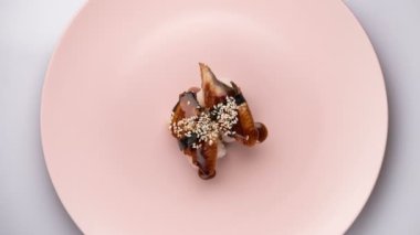 İki yılan balığı nigiri sushi 'nin dönen pembe tabağın en üst görüntüsü..