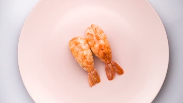 Vista superior de dos camarones nigiri sushi en el plato rosado giratorio . — Vídeos de Stock