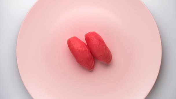 Ovanifrån av spinning två tonfisk nigiri sushi på snurrande rosa plattan. — Stockvideo