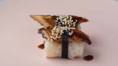 Pembe tabakta dönen iki yılan balığı nigiri suşi..