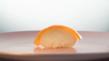 Dönen pembe tabakta somon suşisi. Somon dilimi pirincin üzerine düşer