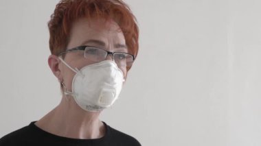 Yaşlı bir kadın evde koruyucu tıbbi maske takıyor, koronavirüs karantinası, yetişkin için beyaz maske..