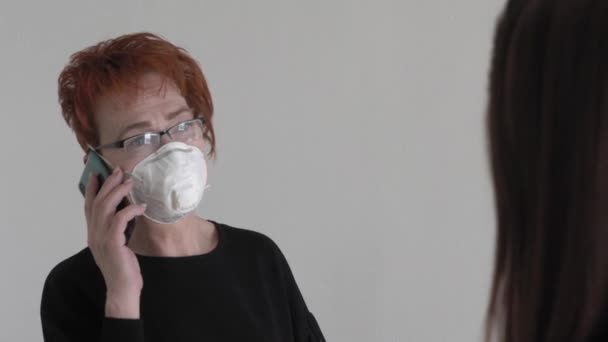 Kontorsarbete under en pandemi COVID-19. Ung affärskvinna och en äldre kvinna talar på smartphone i skyddande masker talar i office coridor. — Stockvideo