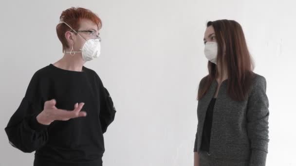 Trabajo de oficina durante una pandemia COVID-19. Joven mujer de negocios hablando en el teléfono inteligente y una anciana con máscaras protectoras están hablando en el pasillo de la oficina . — Vídeos de Stock