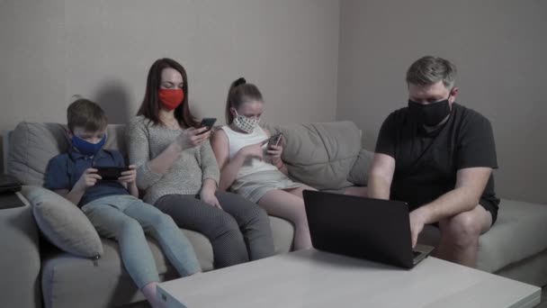 보호용 마스크를 쓴 가족, 코로나 바이러스로 인한 전염병 격리로 집에서 장비를 사용하는 장갑. 엄마, 아빠, 아들 이 함께 컴퓨터로 영화를 보고 있어요. 세계적 인 COVID-19 전염병. — 비디오