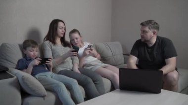 Aile eldivenleri evde koronavirüs salgını karantinasında cihazlar kullanıyor. Anne, baba, oğul ve kız bilgisayarda film izliyorlar. Dünya çapında küresel COVID-19 salgını.