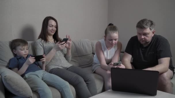 Family gloves using gadgets at home in isolation on coronavirus pandemic quarantine. Mom, dad, son and daughter watching film together on computer. Worldwide global COVID-19 epidemic. — Stock Video