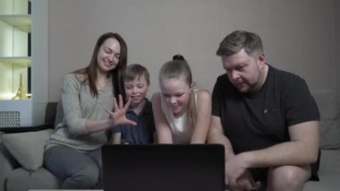 Aile eldivenleri evde koronavirüs salgını karantinasında cihazlar kullanıyor. Anne, baba, oğul ve kız bilgisayarda film izliyorlar. Dünya çapında küresel COVID-19 salgını.