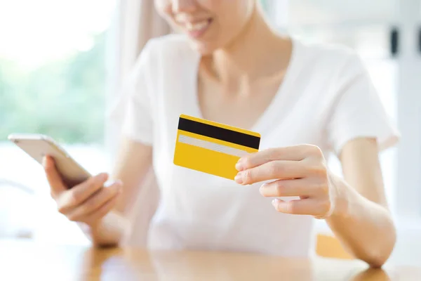Femme heureuse faisant du shopping en ligne avec une carte de crédit et un téléphone — Photo
