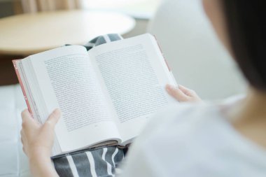 kadın kanepe oturma odasında yatan ona ellerine bir kitapla