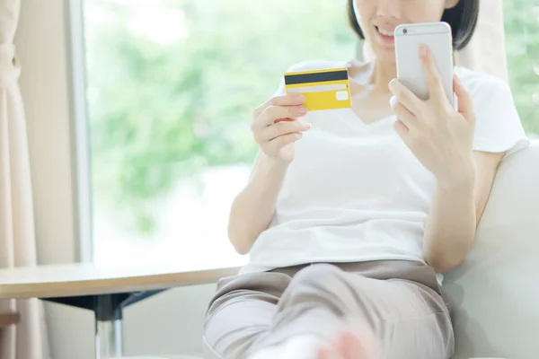 Woman shopping on tablet computer and credit card sitting in sof — Stock Photo, Image