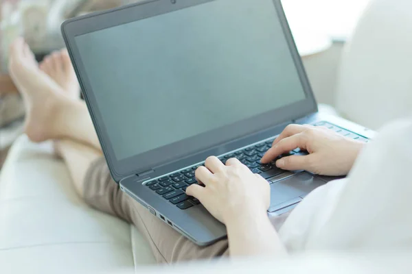 Widok z boku dorywczo młoda kobieta korzysta z laptopa na kanapie w domu — Zdjęcie stockowe