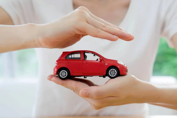 Manos de una mujer de negocios sosteniendo un coche de juguete rojo aislado —  Fotos de Stock