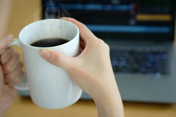 Jovem empresária bebendo café e usando laptop — Fotografia de Stock