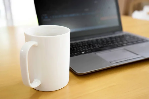 Laptop en koffiekop op houten tafel. Uitzicht van bovenaf — Stockfoto