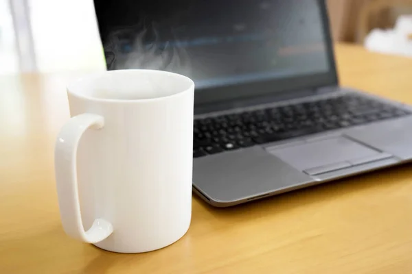 Laptop en koffiekop op houten tafel. Uitzicht van bovenaf — Stockfoto