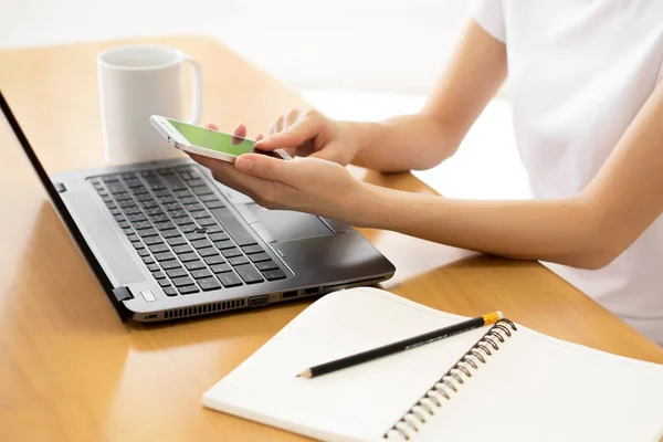 Flickan i händerna håller en mobiltelefon. Laptop med blank — Stockfoto