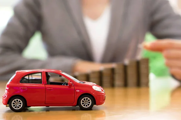 Businesswoman un coche de juguete y una pila de monedas —  Fotos de Stock