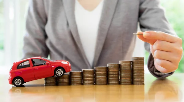 Empresária um carro de brinquedo e uma pilha de moedas — Fotografia de Stock