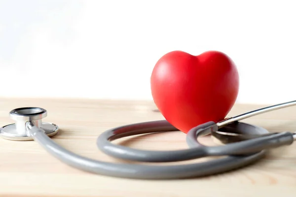 Estetoscópio com coração vermelho em um fundo de madeira — Fotografia de Stock