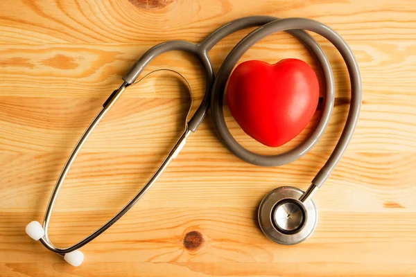Stethoskop mit rotem Herz auf Holz-Hintergrund — Stockfoto